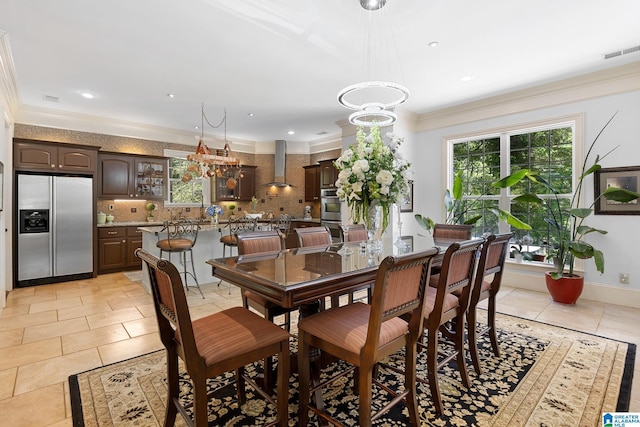 dining area featuring a notable chandelier, ornamental molding, and light tile patterned floors