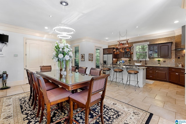 dining space with an inviting chandelier, sink, crown molding, and light tile patterned flooring