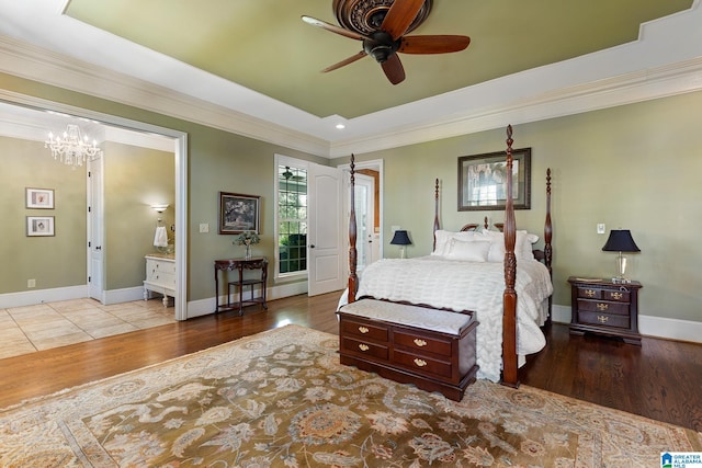 bedroom with ceiling fan with notable chandelier, ensuite bath, ornamental molding, a raised ceiling, and light wood-type flooring