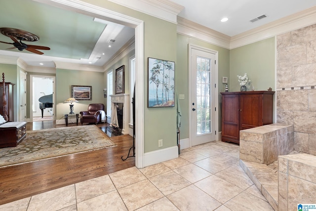 foyer with ceiling fan, light tile patterned floors, a tile fireplace, and a wealth of natural light