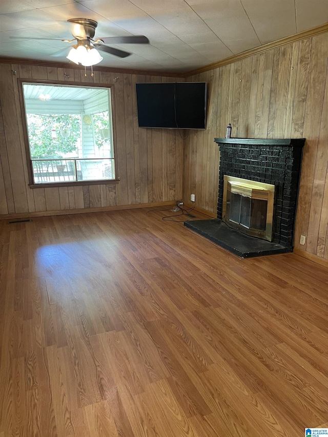 unfurnished living room featuring hardwood / wood-style flooring, ceiling fan, and wooden walls