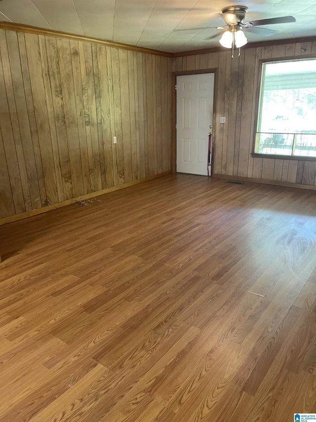 spare room featuring wooden walls, ceiling fan, and light wood-type flooring