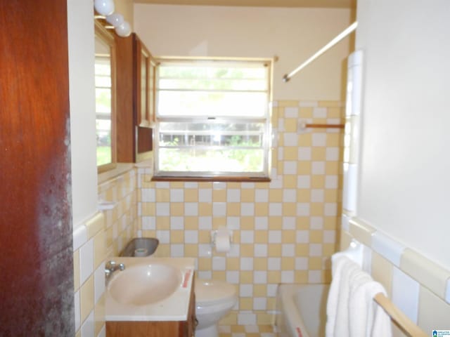 bathroom featuring toilet, a bathtub, walk in shower, vanity, and tile walls