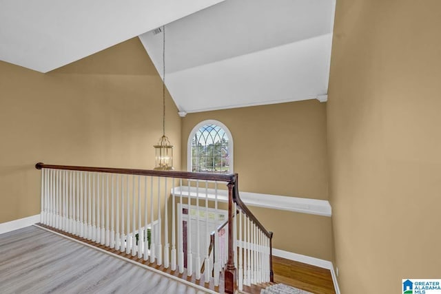 staircase with hardwood / wood-style flooring, vaulted ceiling, and a notable chandelier