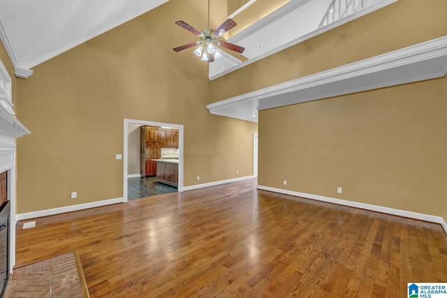 unfurnished living room featuring hardwood / wood-style flooring, ceiling fan, ornamental molding, and high vaulted ceiling