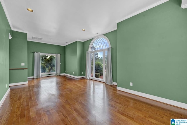 unfurnished living room featuring hardwood / wood-style flooring, ornamental molding, and baseboard heating