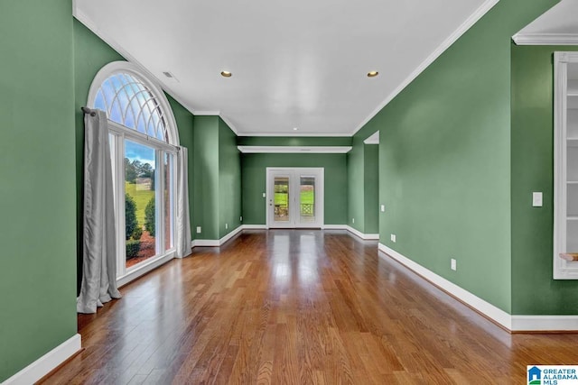 unfurnished living room with hardwood / wood-style flooring, a wealth of natural light, ornamental molding, and french doors