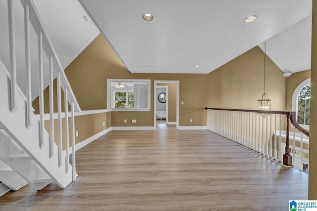 empty room featuring vaulted ceiling, an inviting chandelier, and light hardwood / wood-style flooring