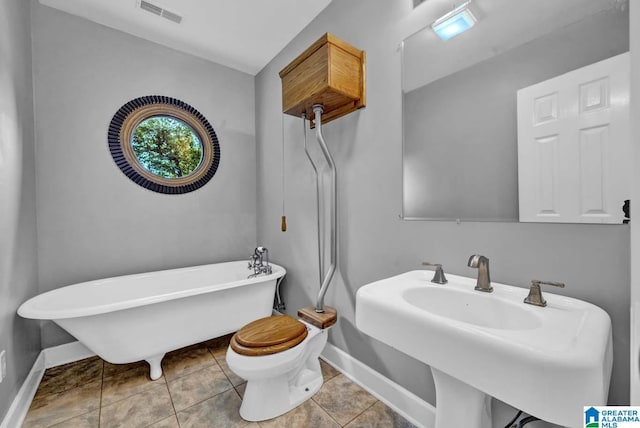 bathroom with a tub to relax in, toilet, tile patterned flooring, and sink