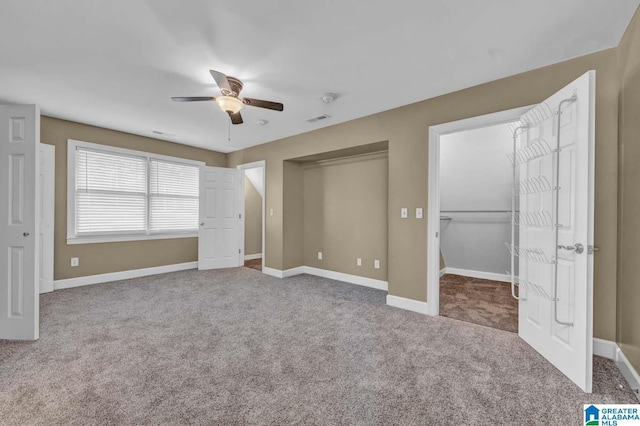 unfurnished bedroom featuring ceiling fan, a spacious closet, and carpet