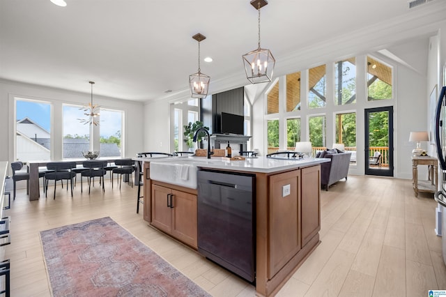 kitchen featuring pendant lighting, light hardwood / wood-style floors, dishwasher, and a kitchen island with sink