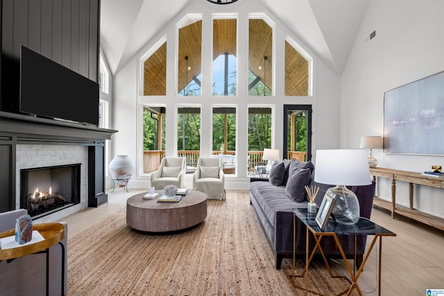 living room featuring a brick fireplace, light wood-type flooring, and high vaulted ceiling