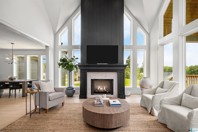 living room with an inviting chandelier, a large fireplace, wood-type flooring, and high vaulted ceiling