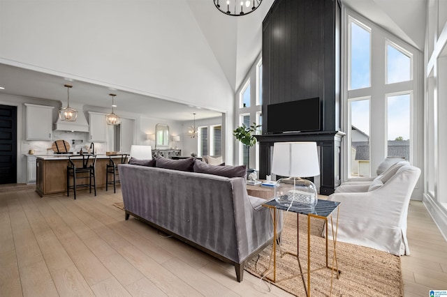 living room with an inviting chandelier, high vaulted ceiling, and light hardwood / wood-style floors