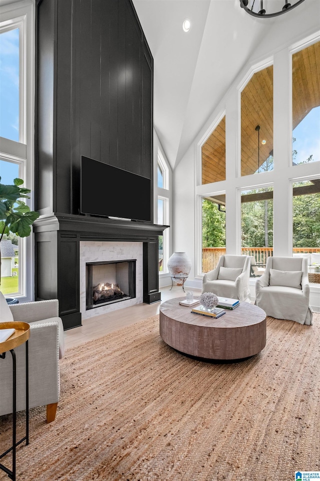 living room featuring a wealth of natural light, a fireplace, high vaulted ceiling, and light hardwood / wood-style floors