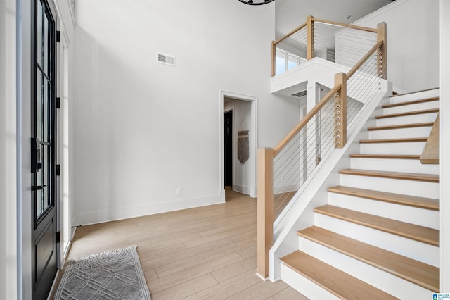 foyer with a towering ceiling and light wood-type flooring