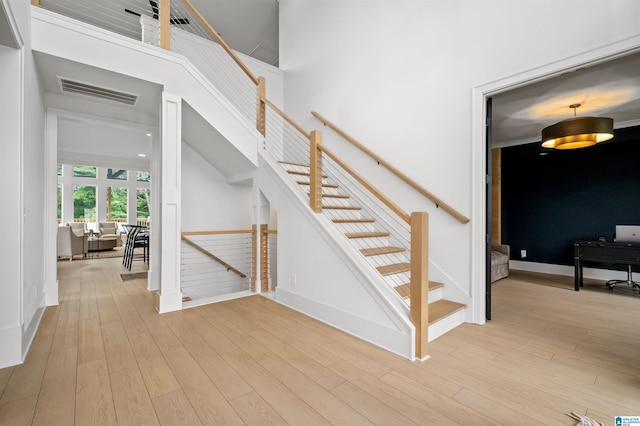 stairs with hardwood / wood-style flooring and a high ceiling