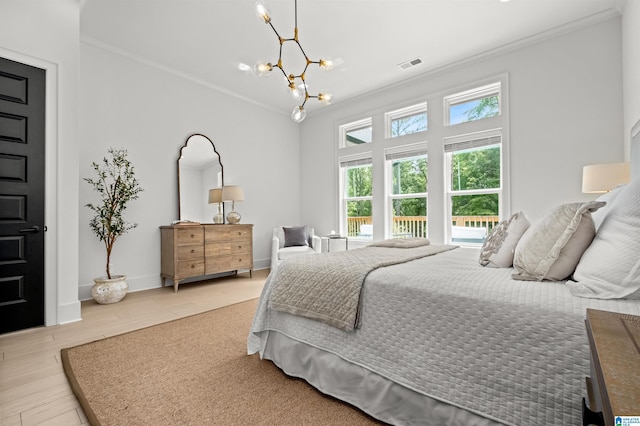 bedroom with crown molding, hardwood / wood-style floors, and a notable chandelier