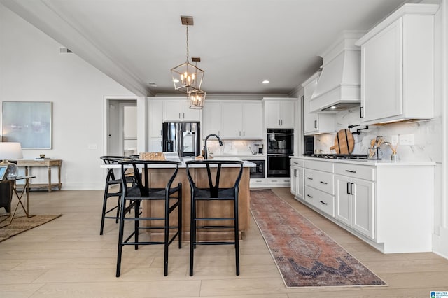 kitchen with an island with sink, appliances with stainless steel finishes, and white cabinets