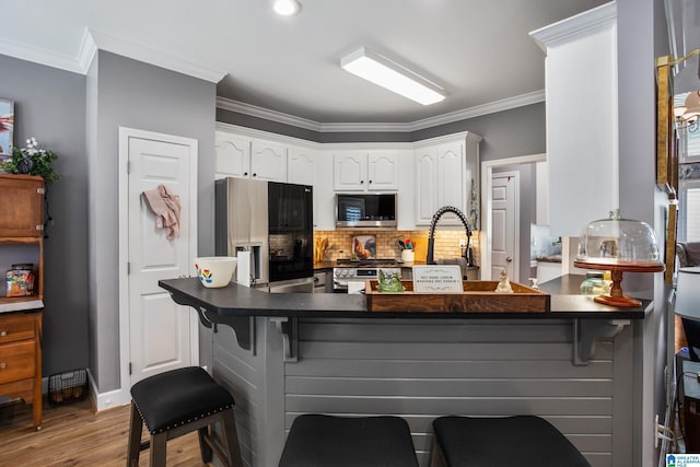 kitchen with black fridge, kitchen peninsula, decorative backsplash, and white cabinets