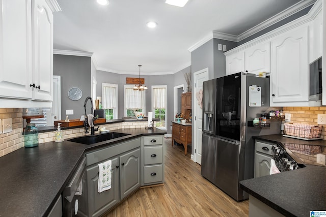 kitchen featuring white cabinetry, sink, backsplash, hanging light fixtures, and an inviting chandelier