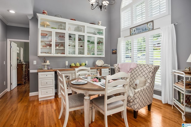 dining area with ornamental molding, a healthy amount of sunlight, a chandelier, and light wood-type flooring