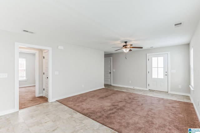 empty room featuring ceiling fan, light carpet, and a wealth of natural light