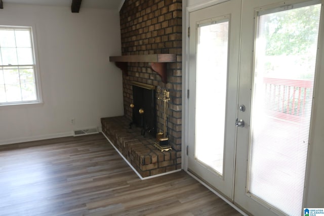 unfurnished living room with hardwood / wood-style floors, a brick fireplace, and french doors