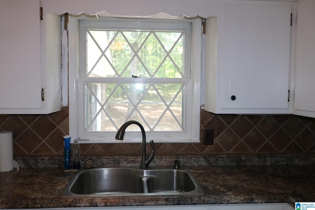 kitchen featuring decorative backsplash, white cabinetry, sink, and dark stone countertops