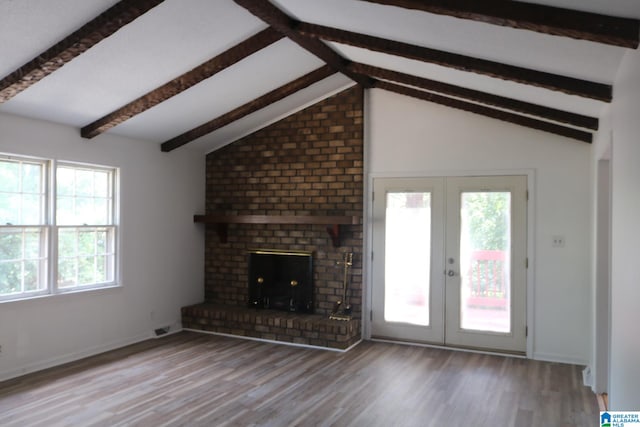 unfurnished living room featuring a fireplace, lofted ceiling with beams, french doors, and light hardwood / wood-style floors