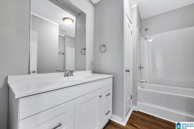 bathroom with hardwood / wood-style floors, a textured ceiling, bathtub / shower combination, and vanity