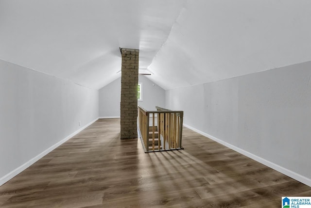 bonus room featuring lofted ceiling, decorative columns, and dark wood-type flooring