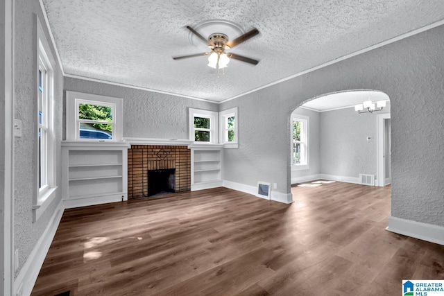 unfurnished living room with ornamental molding, built in features, plenty of natural light, and a fireplace