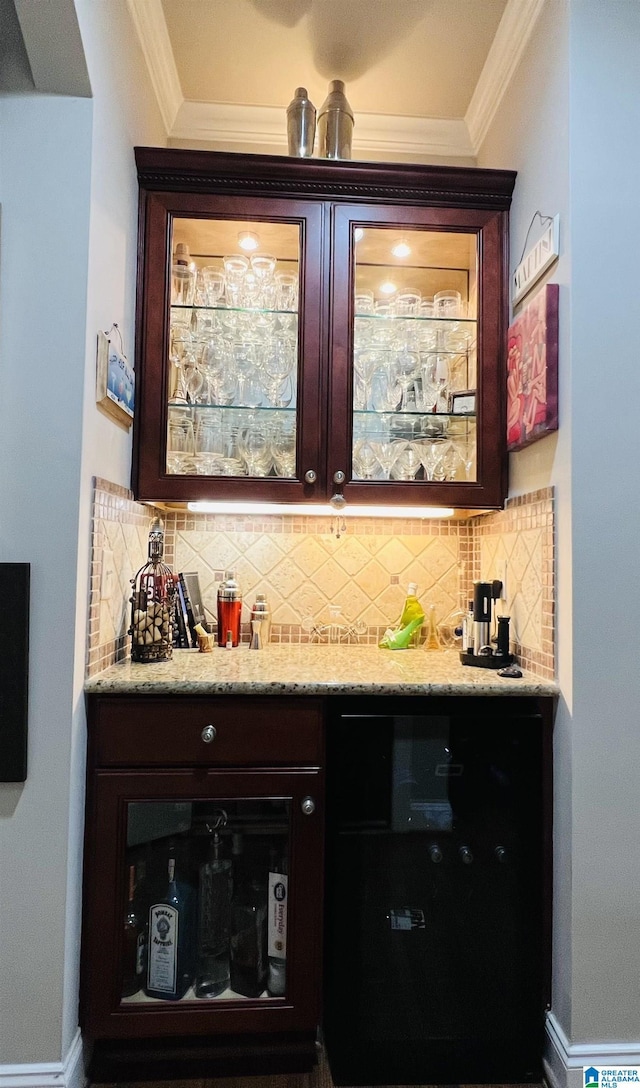 bar with decorative backsplash, light stone countertops, and crown molding