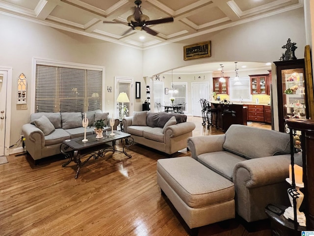 living room featuring ceiling fan, crown molding, wood-type flooring, and coffered ceiling