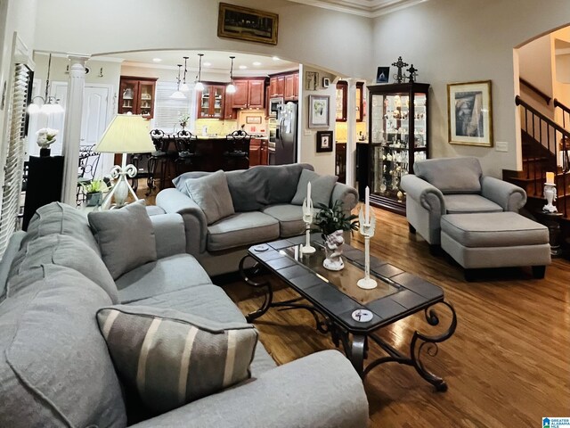 living room featuring decorative columns, dark hardwood / wood-style floors, and ornamental molding