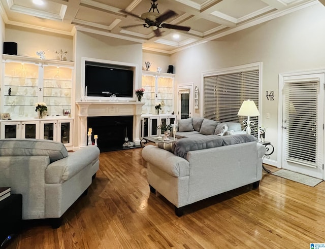 living room with wood-type flooring, crown molding, ceiling fan, and coffered ceiling