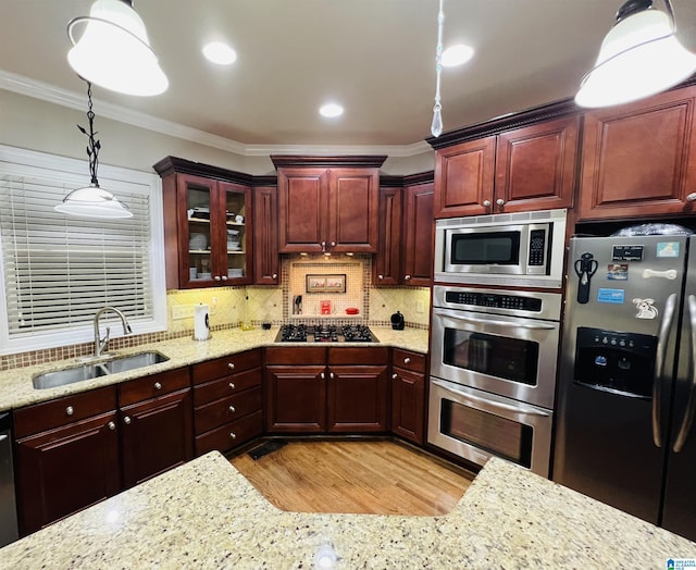 kitchen featuring sink, hanging light fixtures, stainless steel appliances, light hardwood / wood-style flooring, and ornamental molding