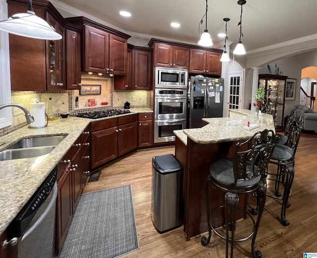 kitchen featuring sink, tasteful backsplash, crown molding, appliances with stainless steel finishes, and light wood-type flooring