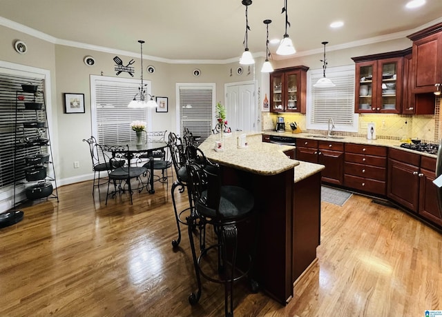 kitchen featuring a breakfast bar, light hardwood / wood-style flooring, hanging light fixtures, and crown molding