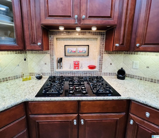 kitchen featuring decorative backsplash, black gas cooktop, and light stone countertops