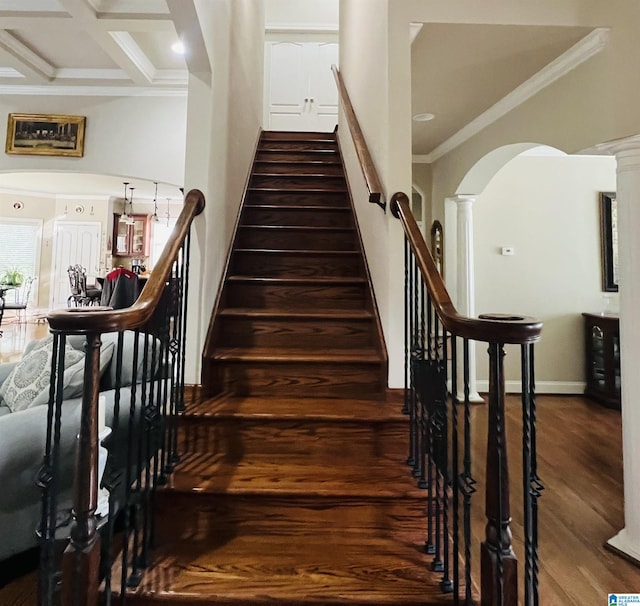 stairway featuring beam ceiling, ornate columns, coffered ceiling, wood-type flooring, and ornamental molding