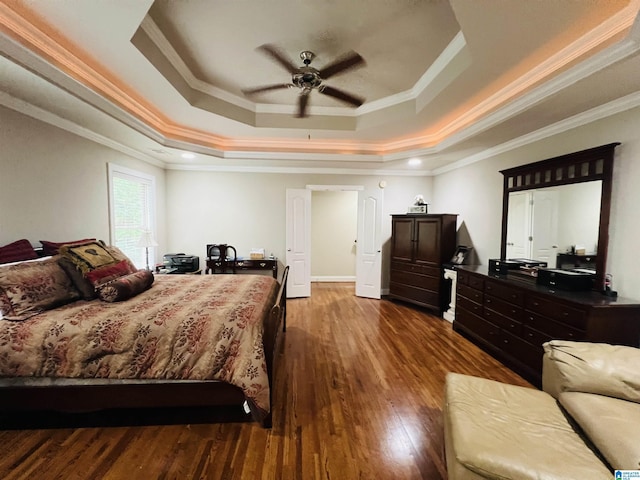 bedroom with hardwood / wood-style flooring, ceiling fan, crown molding, and a tray ceiling