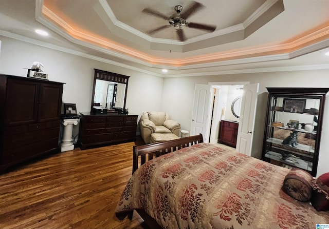 bedroom with dark wood-type flooring, a tray ceiling, ceiling fan, and crown molding