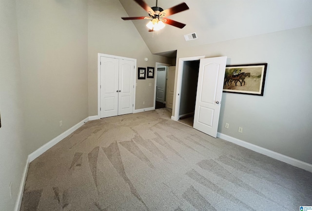 unfurnished bedroom featuring ceiling fan, a closet, high vaulted ceiling, and light carpet