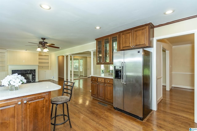 kitchen with light countertops, brown cabinets, glass insert cabinets, and stainless steel fridge with ice dispenser