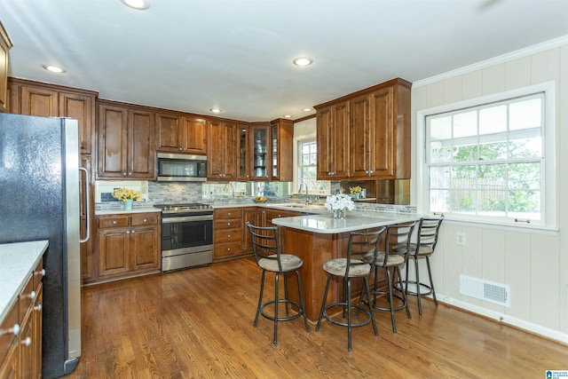 kitchen featuring appliances with stainless steel finishes, a breakfast bar, brown cabinets, and visible vents