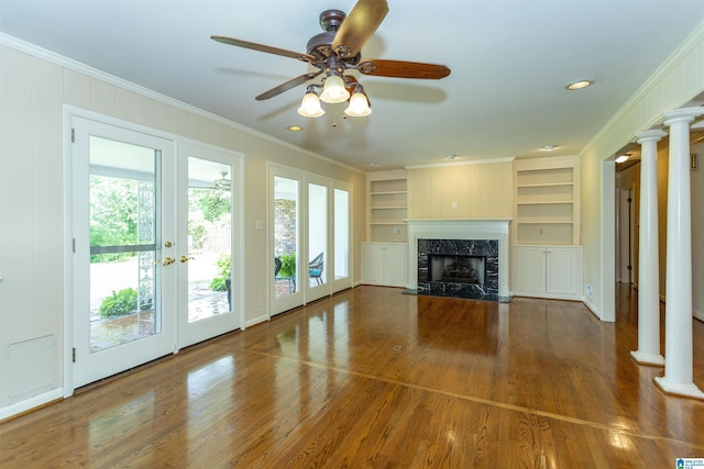 unfurnished living room featuring dark wood-style flooring, a fireplace, french doors, decorative columns, and crown molding