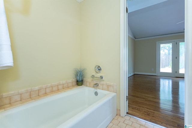 bathroom with lofted ceiling, ornamental molding, tile patterned flooring, and a bath