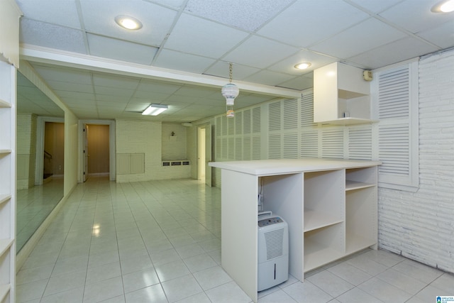 kitchen featuring brick wall, open shelves, and a drop ceiling